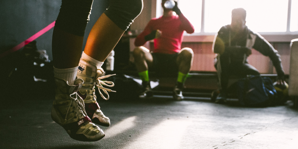 Person jumping in weight room while other watch