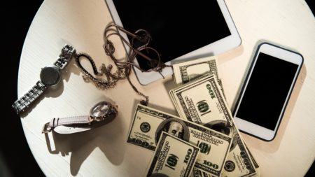 valuables of electronics and jewelry and money on tables