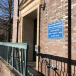 Photograph of the entrance to the property unit (large door on a brick building with railing outside).