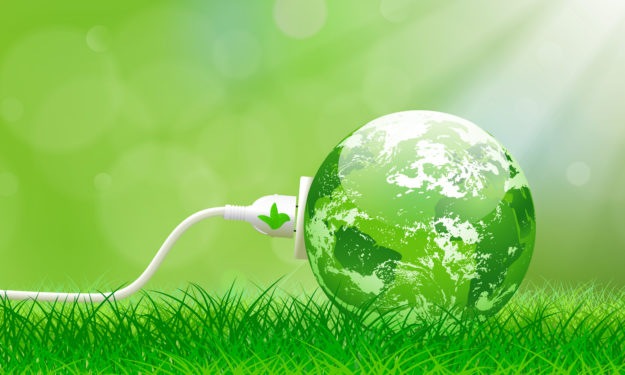 Green energy concept with Planet Earth and electric plug on lush grass