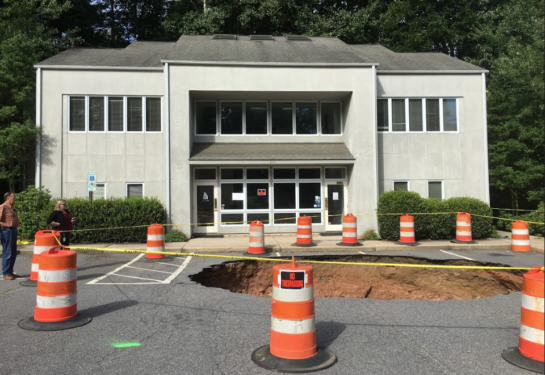 photo of sinkhole in parking lot in front of building