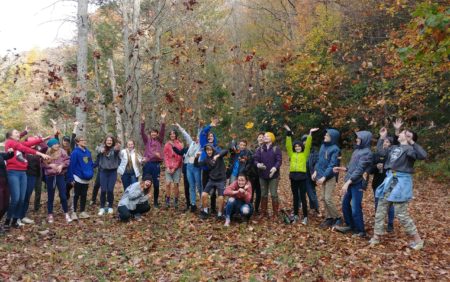 children tossing leaves in the air, with reservoir in background