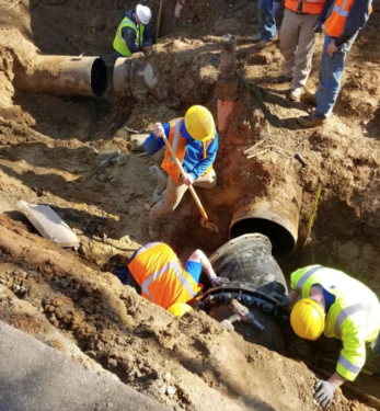 workers in ditch with large water pipes