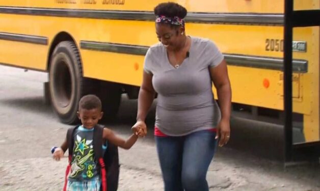 mom holds young student's hand as she walks him from school bus