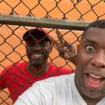 two men at fence at baseball field