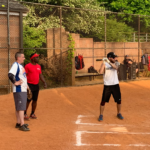 man batting with two men standing behind him