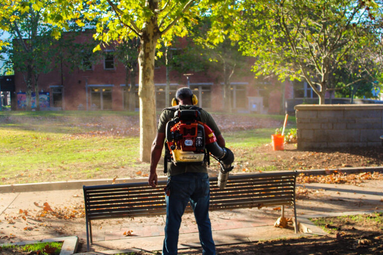 man blowing leaves in park