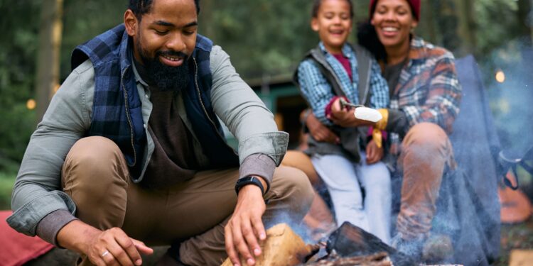 Father building a fire with mom and child in background