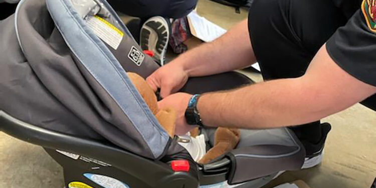 firefighter adjusting straps on infant car seat