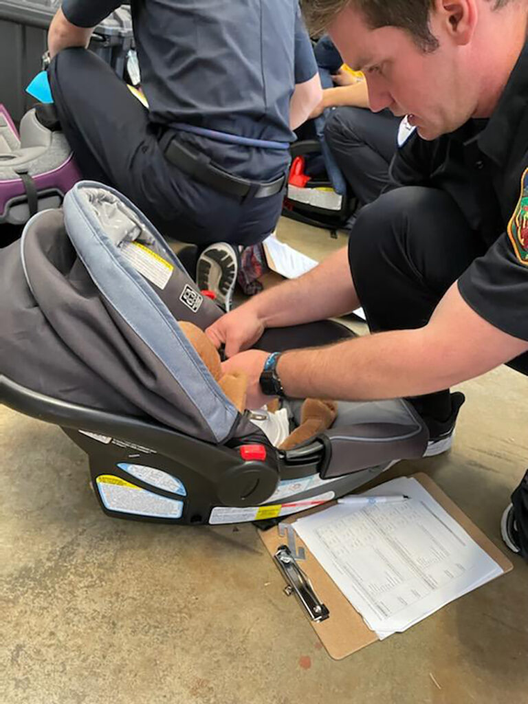 firefighter adjusting straps on infant car seat