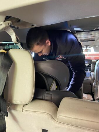 firefighter installing car seat in back seat of car