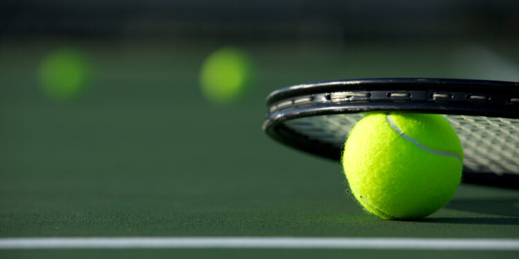 close up view of tennis ball and tennis racket on court