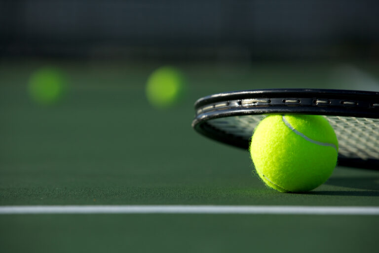 close up view of tennis ball and tennis racket on court