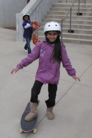 girl wearing purple jacket and white helmet with skateboard