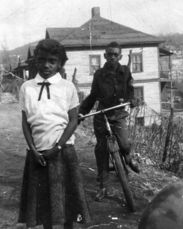 african american girl and boy on bicycle near their home