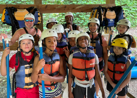 group of kids preparing to go rafting wearing life jackets and helmets