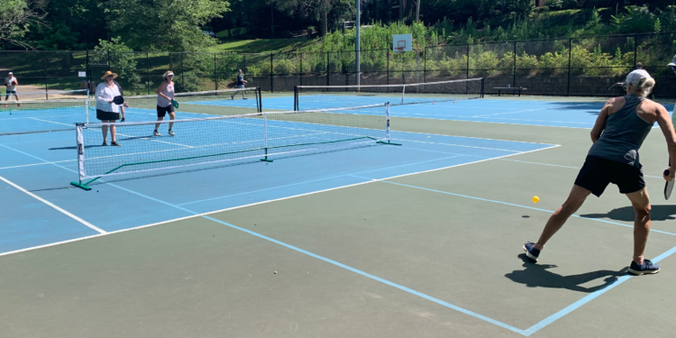 three women playing pickleball on a dual lined court