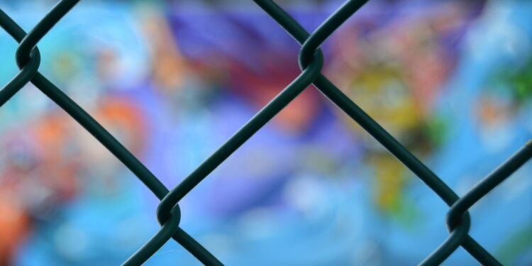 chain link fence with blurred graffiti behind