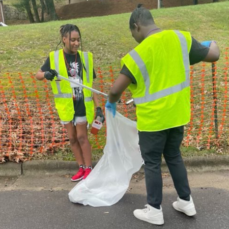 young african american woman and man wearing safety vests picking up trash