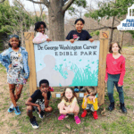 kids at carver edible forest entrance sign