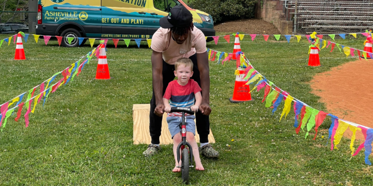 man pushing small child on tricycle