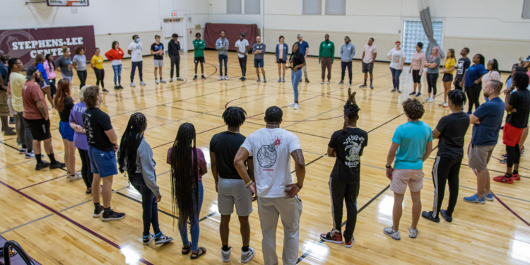 staff standing in circle in a gym preparing for training