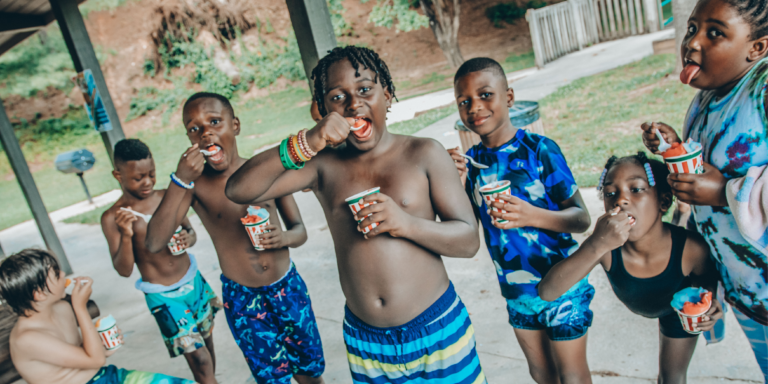 young children eating frozen icees wearing blue swimsuits