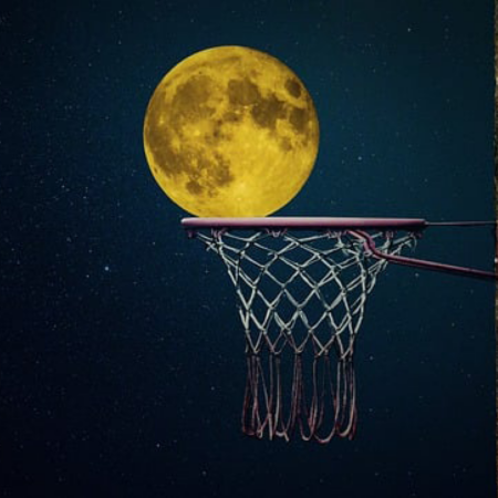 a yellow moon appearing to fall into a basketball goal
