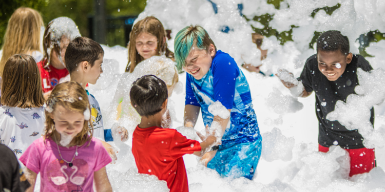 kids playing in bubbles on a blow up slide