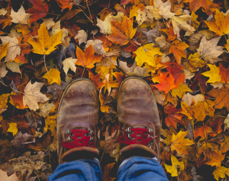 colorful fall leaves on the ground and a pair of boots