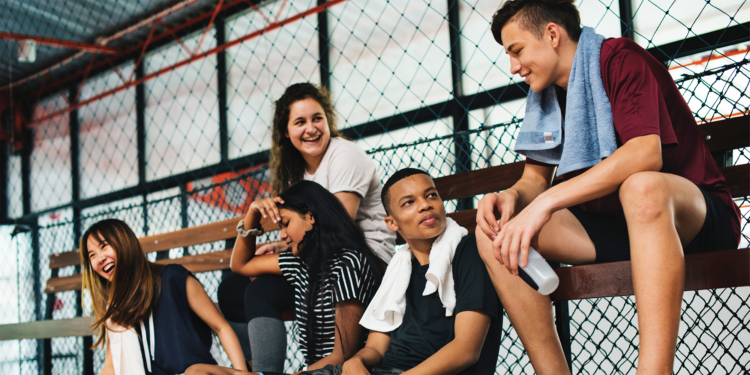 young men and women sitting on bench in gymnasium