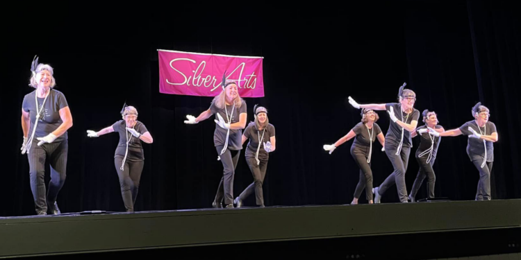 senior ladies dancing on stage with black curtains