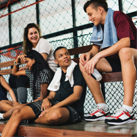 teens gathered sitting on benches in gym clothes