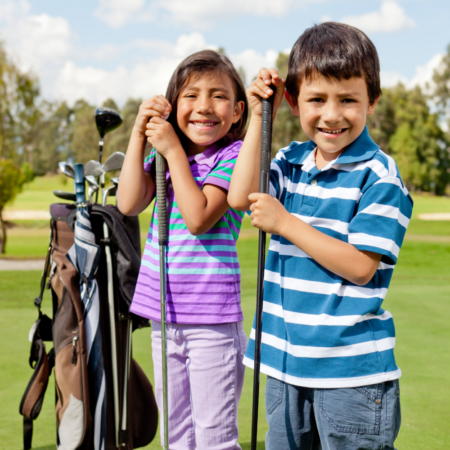 young boy and girl holding golf clubs