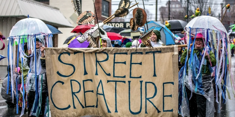 Parade members holding sign that reads street creature