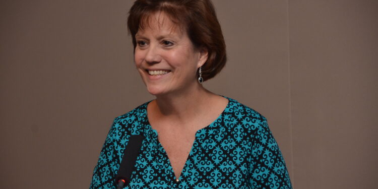 cheryl brown wearing a blue blouse in front of a mic