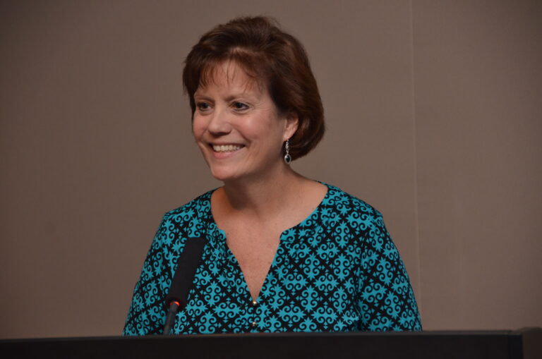 cheryl brown wearing a blue blouse in front of a mic