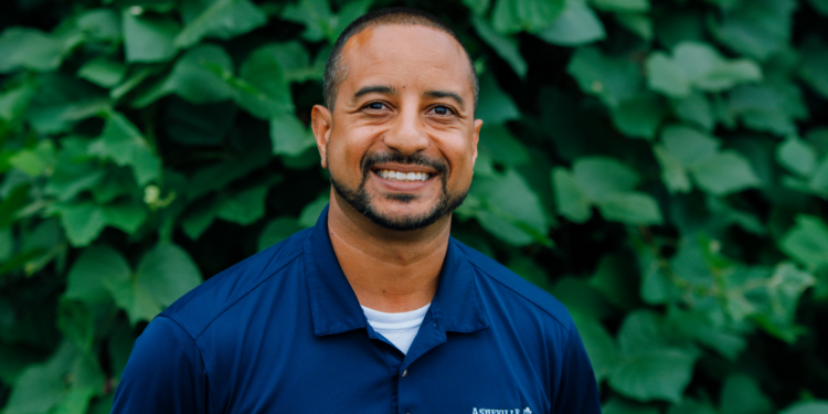 max cherry in clue shirt standing in front of a green background