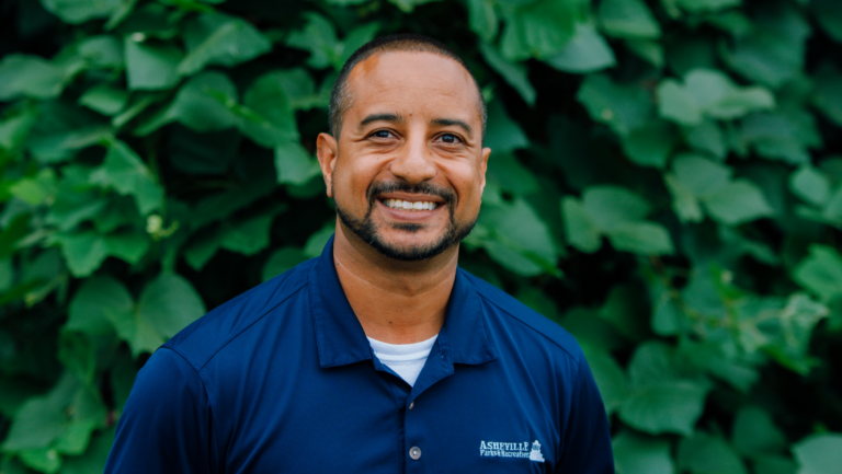max cherry in clue shirt standing in front of a green background