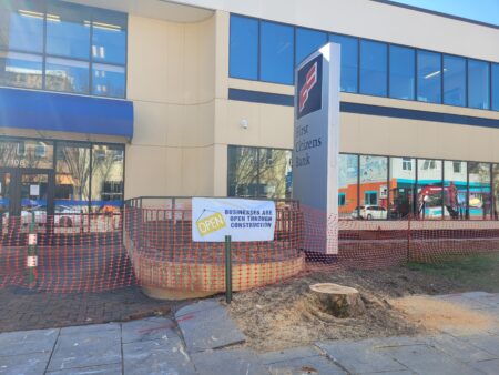 signs posted in work area reminding pedestrians that local businesses are open for business