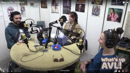 Waht's up AVL host Sam Parada in studio with guest Kiera Bulan and Aurora Wynne. The three sit around a table with mics as they record podcast