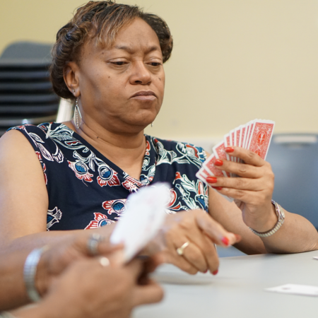 lady wearing blue floral shirt holding a hand of cards