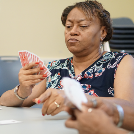 lady wearing blue floral shirt holding a hand of cards