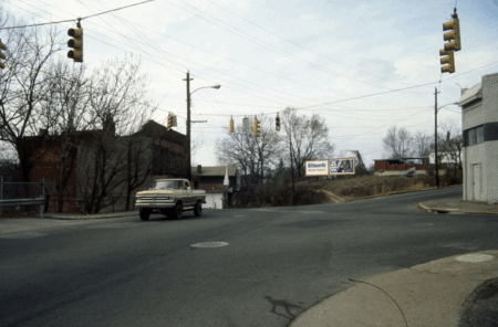 truck driving in front of dilapidated buildings
