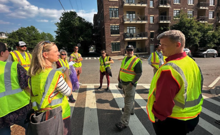 community members in hi-viz vests in a cross walk downtown