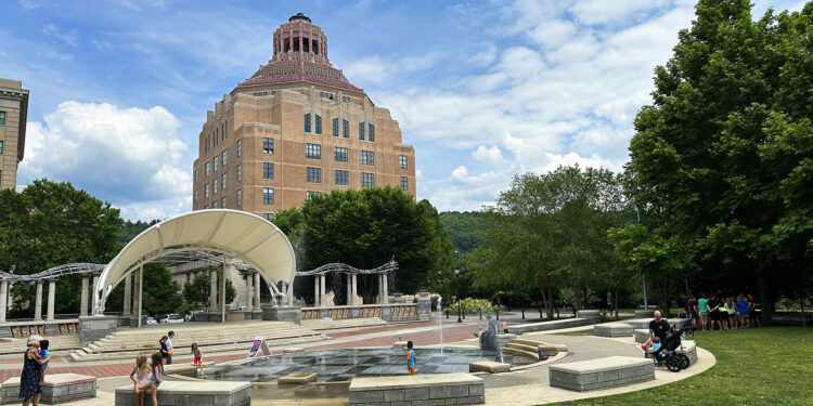 City Hall in background with Splasheville and residents in foreground on a bright smmer day