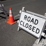 road closed sign near roadway with orange caution cone