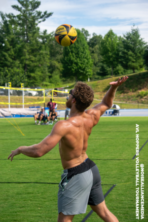 African american man playing volleyball on grass court