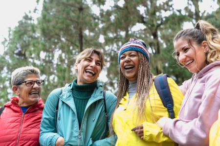group of 4 women wearing outdoor clothing and laughing