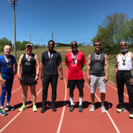six men wearing athletic wear standing on track